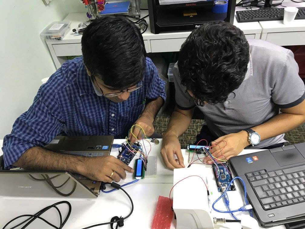 Close-up of Arduino boards wired to sensors and a breadboard on the classroom bench
