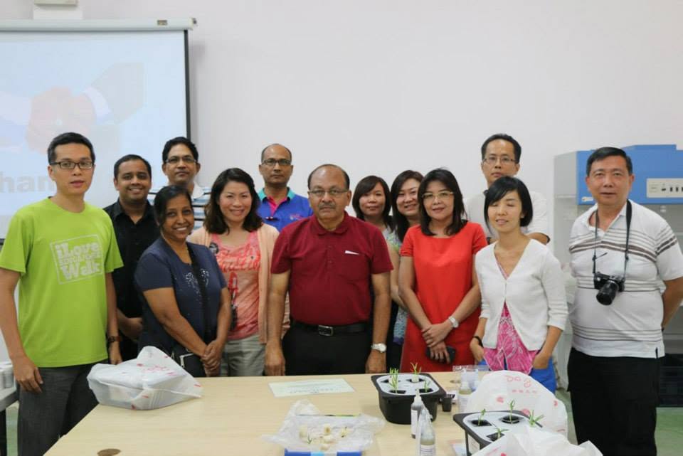 The 8 March 2014 hydroponics class posing together, with Dr Mallick in a maroon shirt at the centre and completed hydroponic starter kits on the table in front