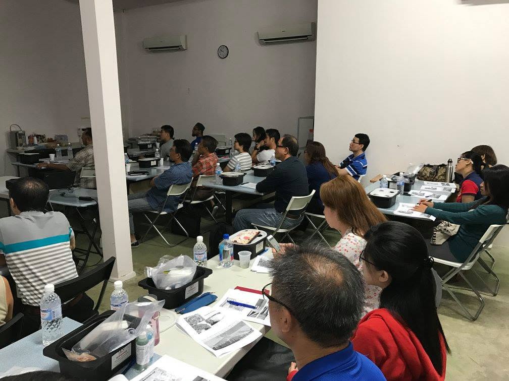 Participants seated at tables working with their black hydroponic grow tubs and lids during the practical session