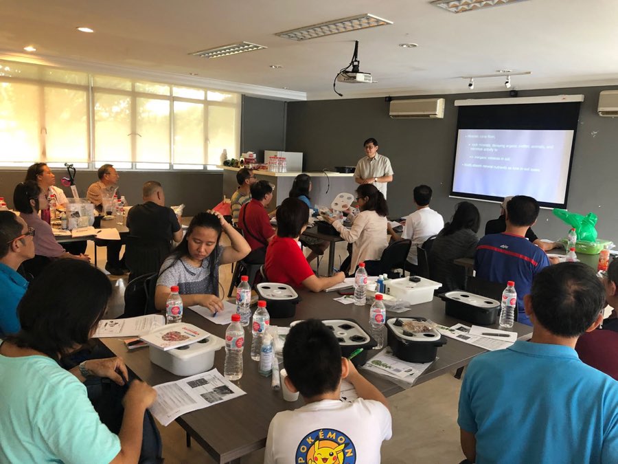 Participants seated at tables in a classroom during the indoor urban farming session, with kits and notes in front of them