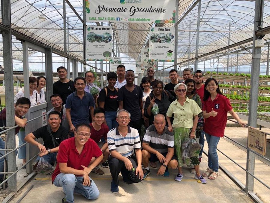 The 15 February 2020 hydroponics class posing together inside the Showcase Greenhouse at a commercial Singapore hydroponics farm, with growing benches visible on both sides