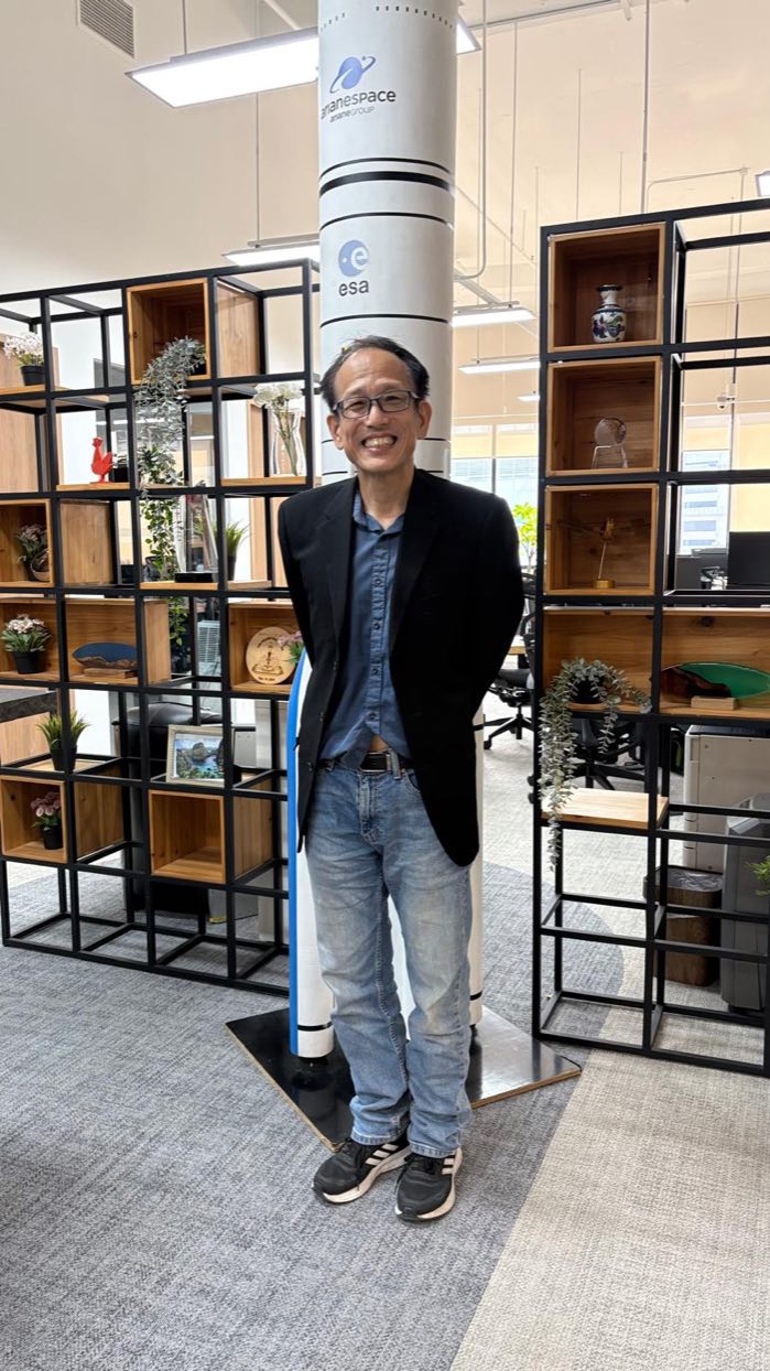 Dr. Alfred Ang at the Kacific Satellite Broadband office in Singapore, beside a model of the Ariane launch vehicle.